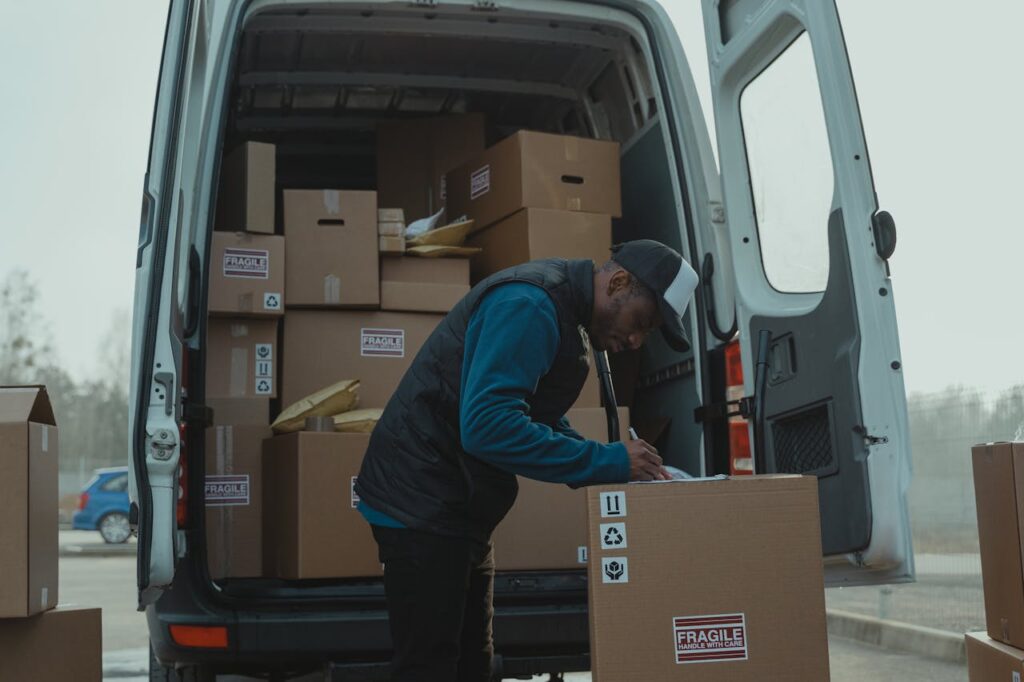 pexels-photo-6169188 Delivery man sorting packages in van, organizing shipments for distribution.